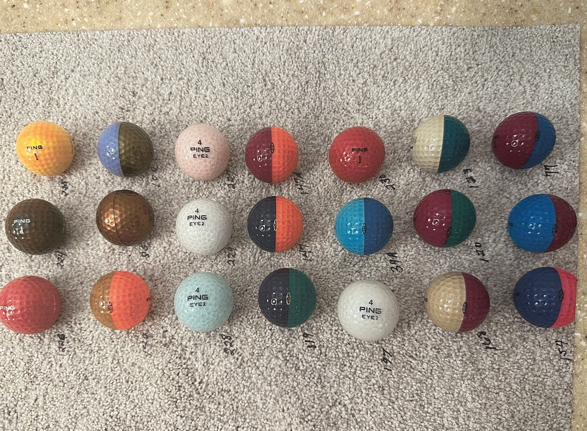 Ping golf balls with catalog reference numbers arranged on towel showing various two-tone color combinations
